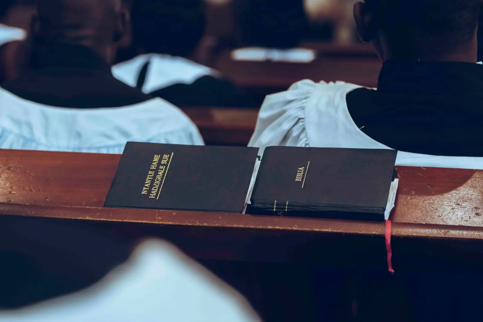 A Bible and a hymn book resting on a wooden pew