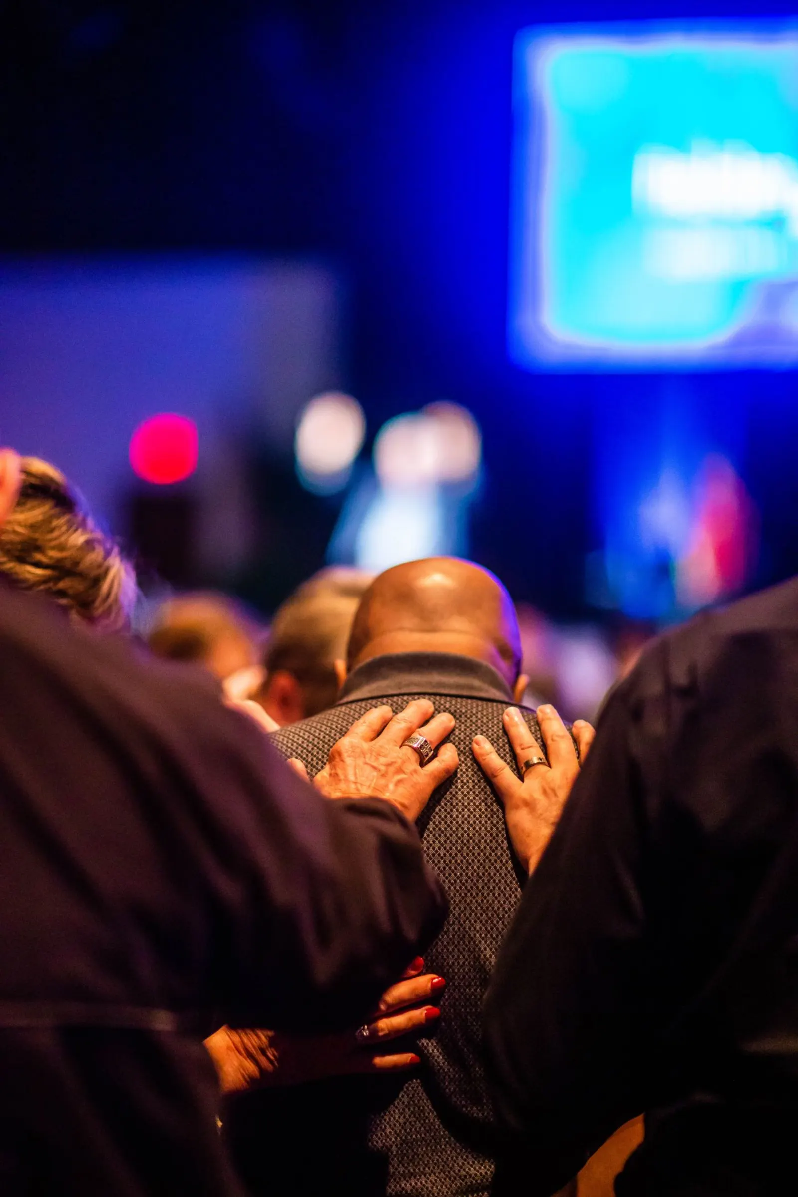 Hands laid on a leader's shoulders during a commissioning service